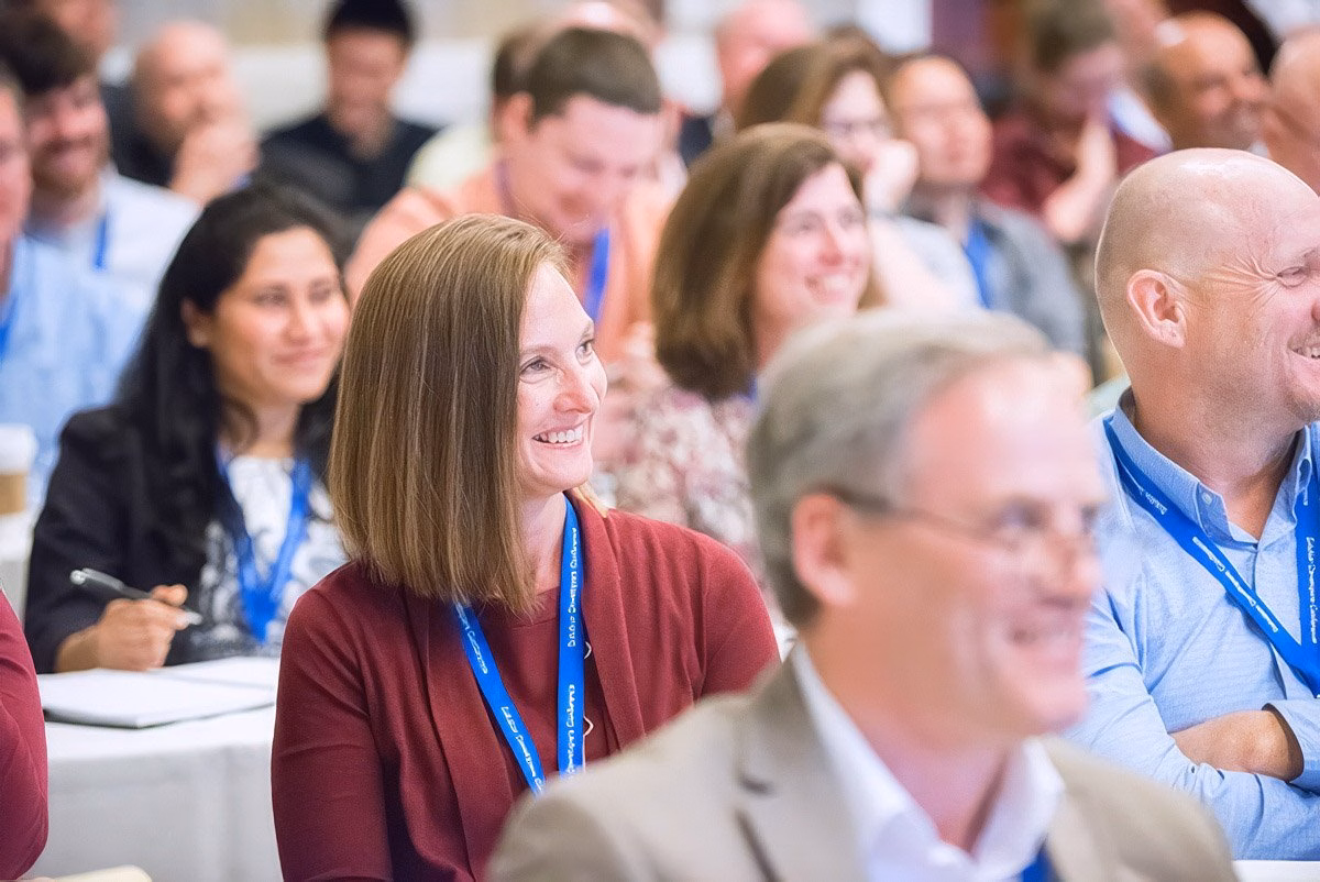 Smiling audience members at a corporate event in Boston.