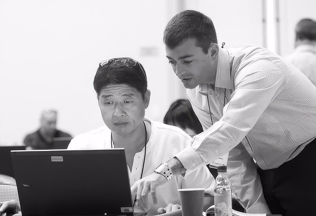 Two men collaborating over a laptop in a corporate setting.