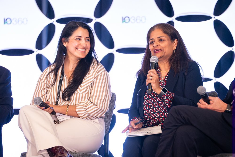 Two women speaking at a panel discussion with a backdrop featuring the 10 360 logo.