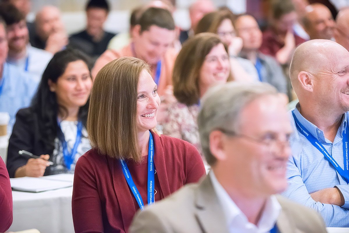 Smiling audience members at a corporate event in Boston.