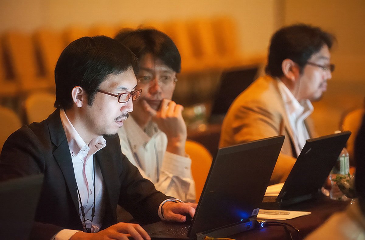 Three professionals working on laptops at a corporate event in Boston.