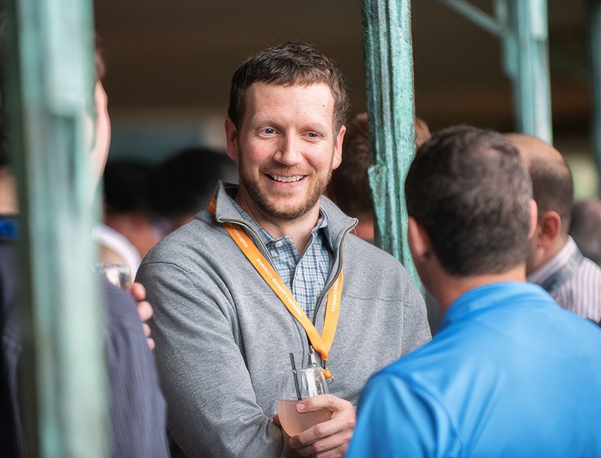 Conference attendee smiling and holding a drink, with a networking atmosphere in Boston.