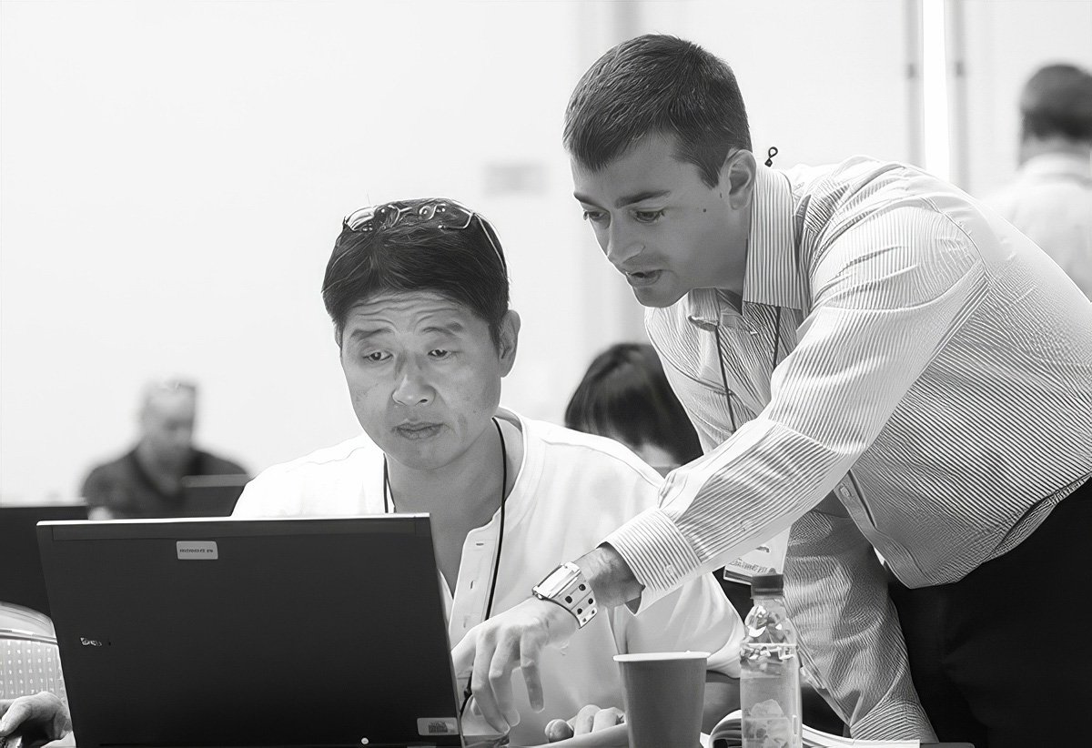Two men collaborating over a laptop in a corporate setting.