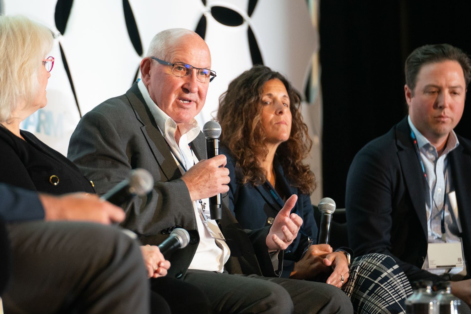 Panel discussion with four speakers, one actively speaking into a microphone.