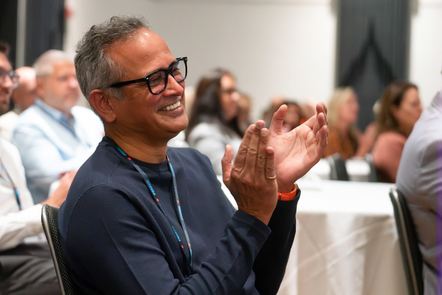 Man smiling and clapping at a corporate event in Boston.