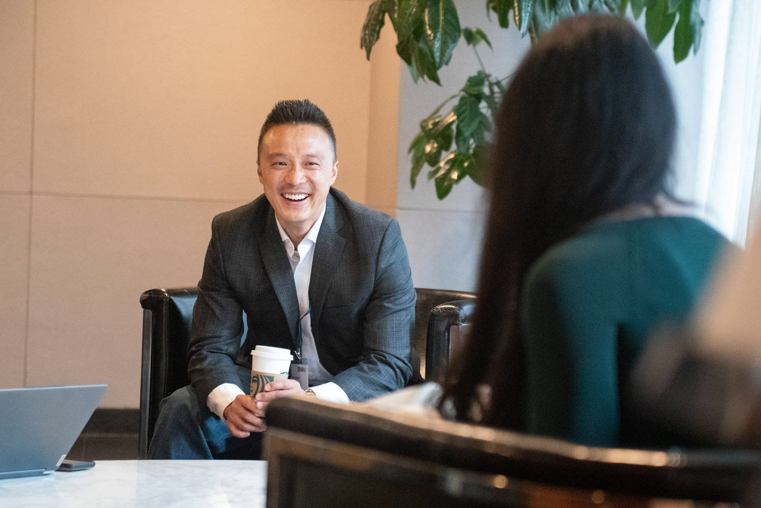 Business professional smiling with coffee during a corporate event in Boston.