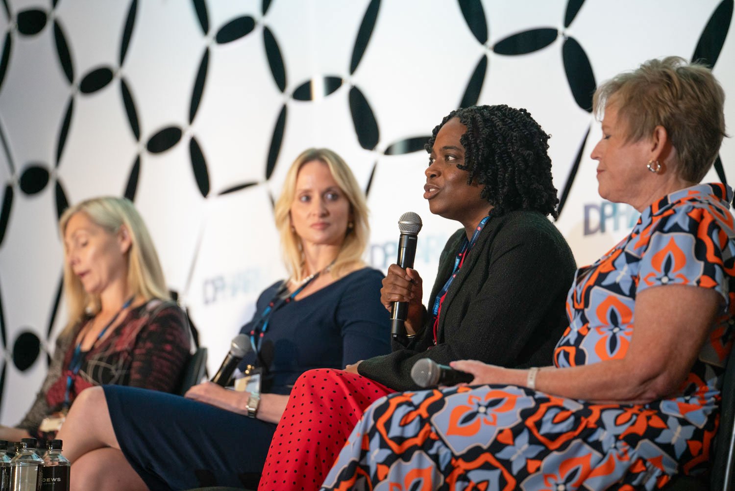 Four women speaking on a panel at a corporate event in Boston