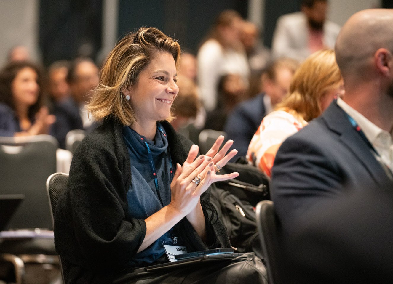 Woman smiling and clapping at a corporate event in Boston.